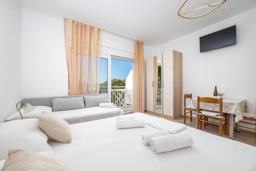 a white living room with a couch and a table at Rosemary Apartments in Duće