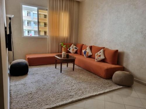 a living room with an orange couch and a table at Appartement agadir centre in Agadir