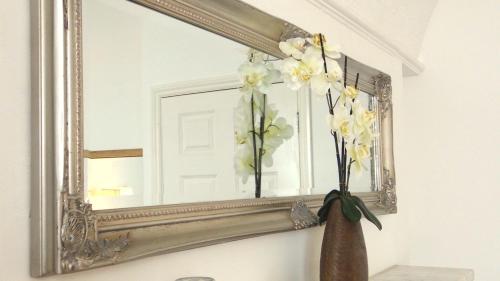 a mirror with a vase of flowers in front of it at Jessamine House Hotel in Gravesend