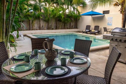 a table with plates and chairs next to a pool at Casa NAJ BALAM in Bacalar