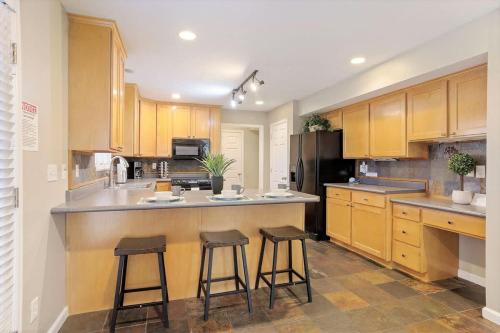 a kitchen with wooden cabinets and two bar stools at Union Park in Salt Lake with Hot Tub Near Park in Midvale