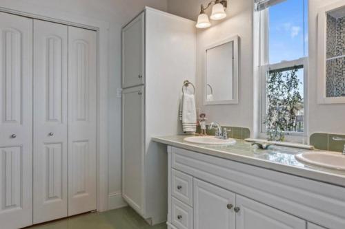 a white bathroom with two sinks and a window at Paradise Beachfront Firepit Couples Retreat in Caplen