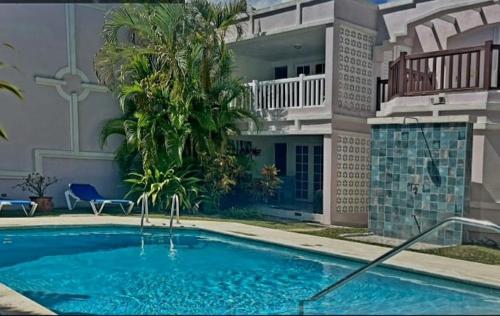 a large swimming pool in front of a house at Amaryl The Dream St Lawrence Gap 2BR condo with pool in Christ Church