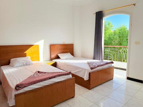 two beds in a room with a large window at Nile View House in Luxor