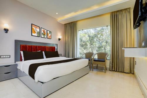 a bedroom with a large bed and a large window at Hotel O namaste doon in Rājpur