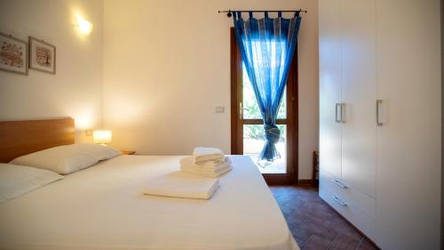 a bedroom with a bed and a window with blue curtains at Li Chessi Blu Villetta Familiare con Piscina in Costa Paradiso