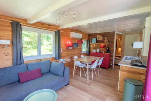 a living room with a blue couch and a table at Le lodge sur pilotis in Fichous-Riumayou
