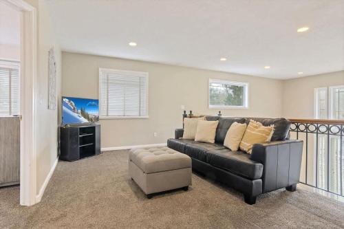 a living room with a black couch and a chair at Union Cove 3-Plex in Salt Lake with Hot Tub in Midvale