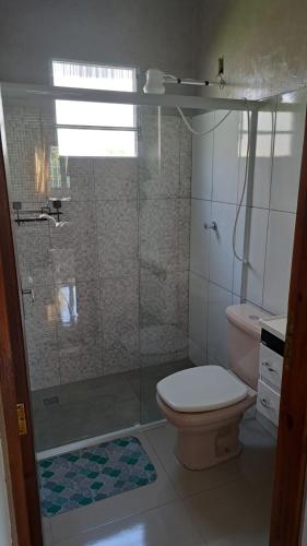 a bathroom with a toilet and a glass shower at Chalé Zarinha I in Serra Negra