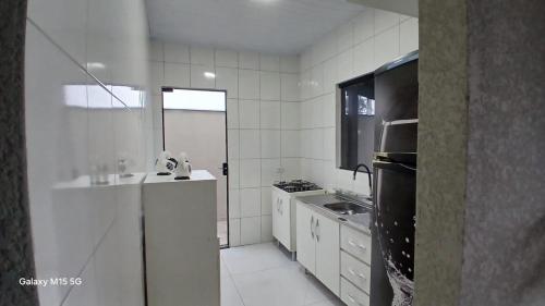 a white kitchen with a sink and a refrigerator at aconchegante com piscina e churrasqueira, pertinho da praia" in Itapoa