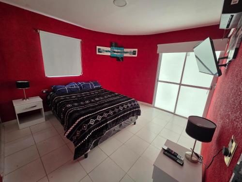 a bedroom with red walls and a bed with blue pillows at Alisos Suite FC in El Ceibal