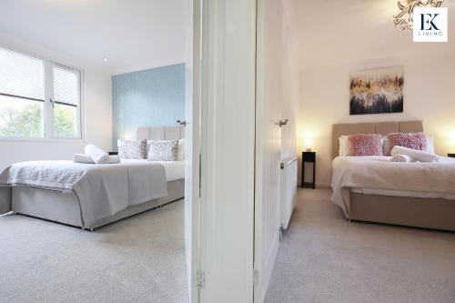 ein weißes Schlafzimmer mit zwei Betten und einem Spiegel in der Unterkunft Luxury Group Stay With Bar, 80-inch TV and Parking - Sleeps 10 - By EKLIVING 