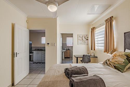 1 dormitorio con 1 cama con silla y cocina en Upstairs at 47, en Centurion