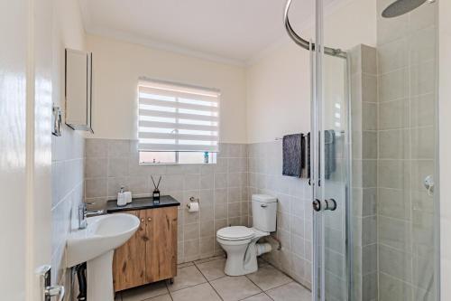 Un baño con inodoro, lavabo y ducha. en Upstairs at 47, en Centurion