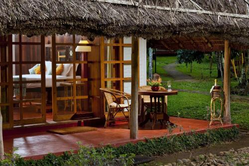 a small hut with a table and a bed at Spice Village Thekkady - CGH Earth in Thekkady