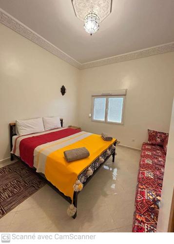 a bedroom with a bed with a yellow and red blanket at Dar Éthiqua in Essaouira