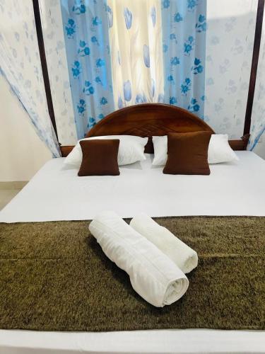 two beds with white sheets and brown pillows at Sahas Homestay in Tangalle