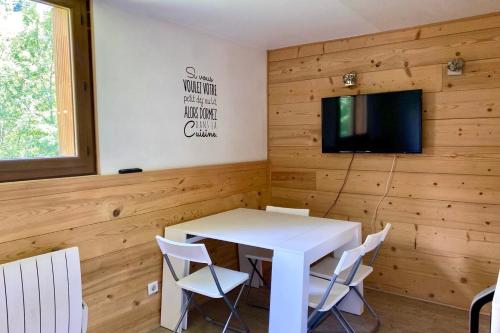 Una habitación con una mesa y sillas blancas y un televisor. en Bright apartment near the slopes, en La Salle-les-Alpes