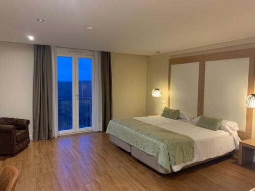 Un dormitorio con una cama grande y grandes ventanales. en Hotel MedinaSalim, en Medinaceli