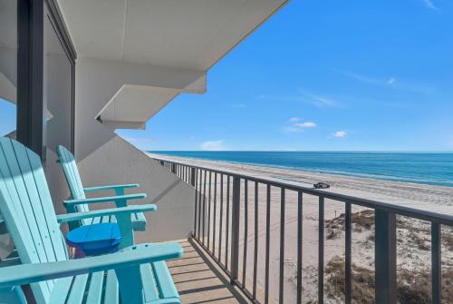 a balcony with two blue chairs and the beach at Island Winds East Condo 402 in Gulf Shores