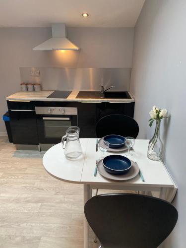 une cuisine avec une table avec des assiettes et des verres dessus dans l'établissement Les studios Happy - Local vélo, à Verdun-sur-Meuse