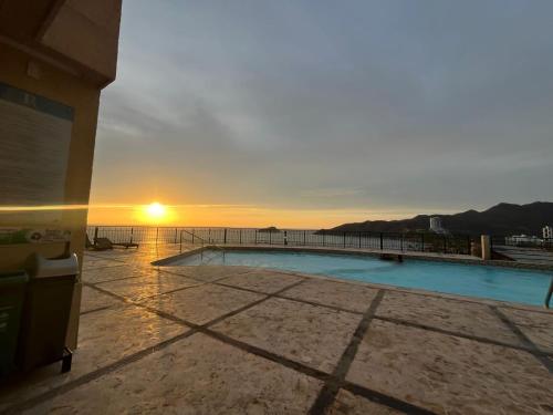 a swimming pool with the sunset in the background at Peñon del rodadero reservas in Puerto de Gaira
