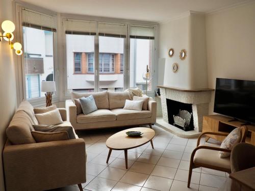 een woonkamer met een bank en een open haard bij Charmante Villa 5 min de la plage et garage in Le Touquet-Paris-Plage
