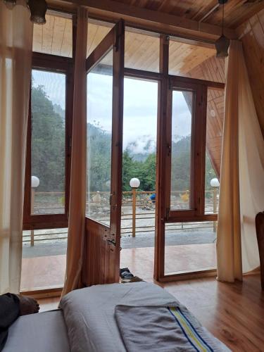 a bedroom with a large window with a view of a mountain at Nirvana River Nest in Sainj