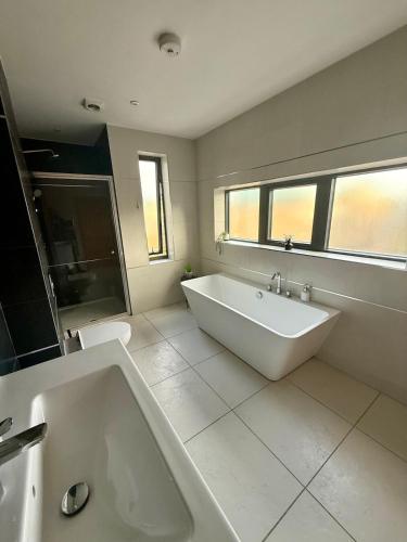 ein großes weißes Badezimmer mit einer Badewanne und einem Waschbecken in der Unterkunft Charming Ensuite Retreat in a Premier Location in Brentford