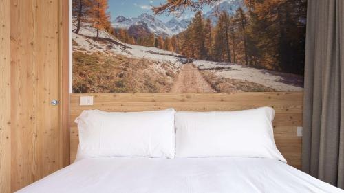a bedroom with a bed with a painting on the wall at L'essenza Chalet - San Pietro 8A Valdisotto in Bormio