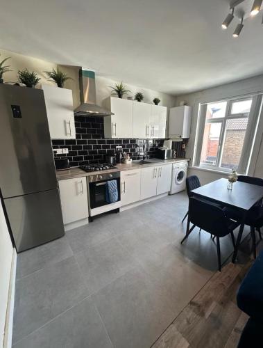 a kitchen with white cabinets and a table in it at HP Wizards Corner Spacious 4 bed near Watford Junction in Watford