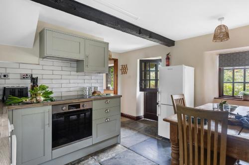 a kitchen with green cabinets and a table and a refrigerator at Myrtle Grove in Saint Endellion