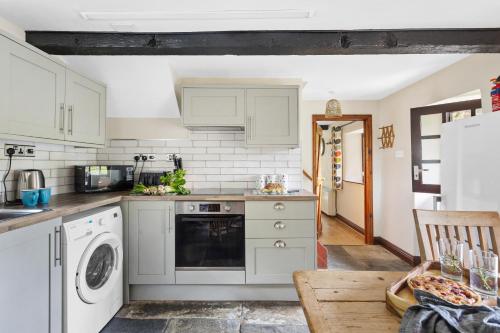 a kitchen with white cabinets and a dishwasher at Myrtle Grove in Saint Endellion