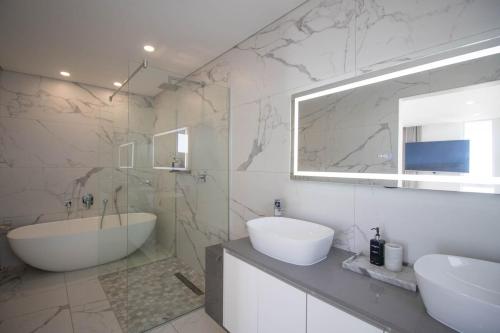 een badkamer met een bad, een wastafel en een tubermottermott bij Ocean Dream Beach Villa in Yzerfontein