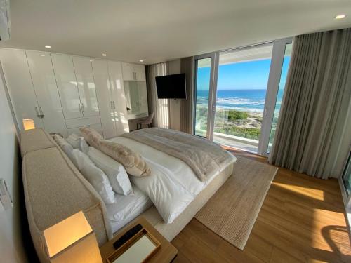 een slaapkamer met een groot bed met uitzicht op de oceaan bij Ocean Dream Beach Villa in Yzerfontein