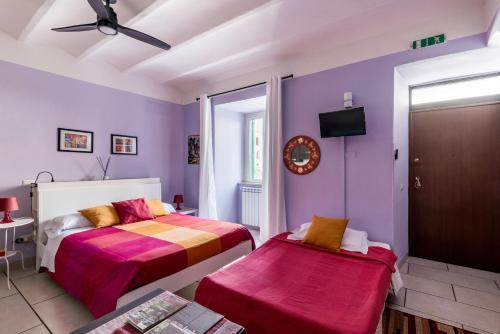 a bedroom with two beds and purple walls at Appartamento Tivoli Train Station in Tivoli