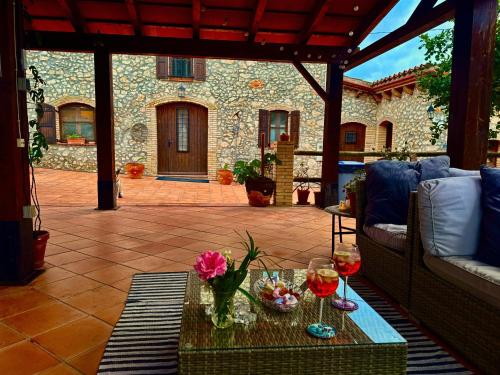 a patio with a couch and a table with wine glasses at Mas del Drac in Castellví de la Marca