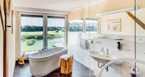 a bathroom with a tub and two sinks and a window at Erlebnishotel "Zur Schiffsmühle" GmbH in Höfgen