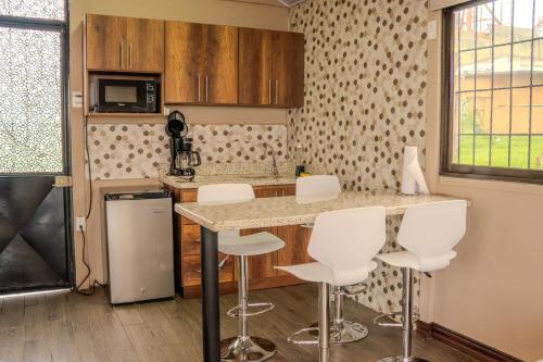 a kitchen with a counter and white stools at Cabañas La Montañuela in Llano Grande