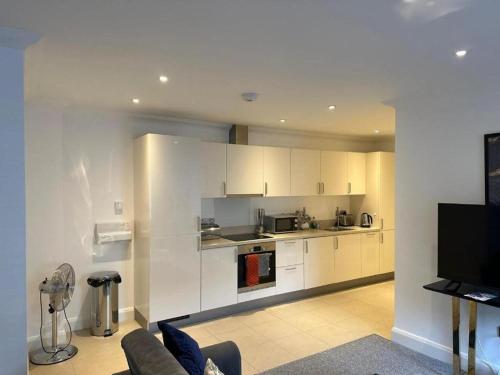 a kitchen with white cabinets and a living room at The Cassius Apartment Huntingdon in Huntingdon