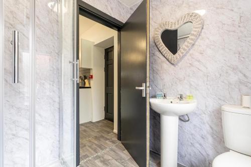 a bathroom with a toilet and a sink and a mirror at Spacious 6-Bed Stay Central Warrington Sleeps 12 in Warrington
