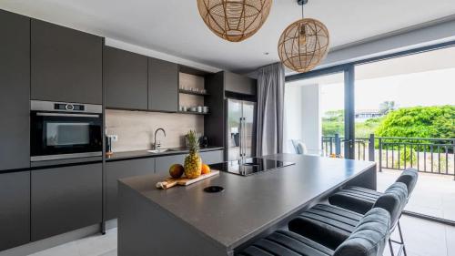 a kitchen with black cabinets and a island with chairs at Dushi Breeze in Blue Bay