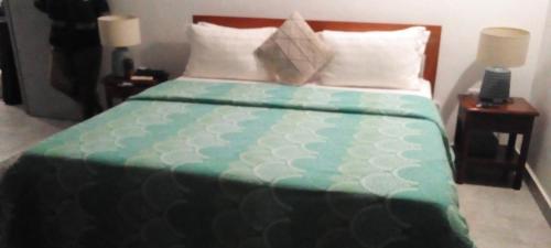 a bed with a green and white comforter and pillows at Malombo Selous Forest Camp in Kwangwazi