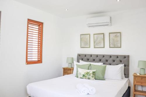 Sapphire Residence في فيليمستاد: غرفة نوم بها سرير أبيض مع لمسات خضراء