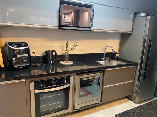 a small kitchen with a sink and a microwave at Belíssimo apartamento em Porto Alegre! in Porto Alegre