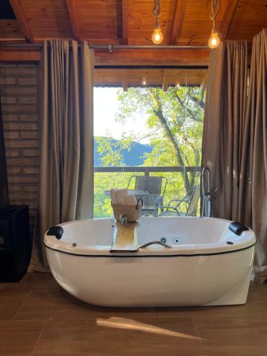 a white tub in a room with a window at Chalé Refúgio Panorâmico in Canela