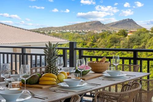 a table with fruit and wine glasses on a balcony at Azure Penthouse in Willemstad