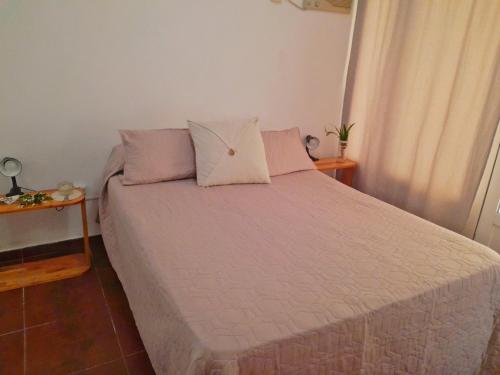 1 dormitorio con 1 cama con sábanas y almohadas rosas en Kalma, en Villa Elisa