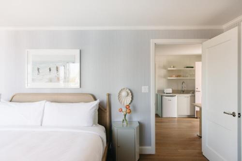 a white bedroom with a bed and a kitchen at Bay Shores Peninsula Hotel in Newport Beach