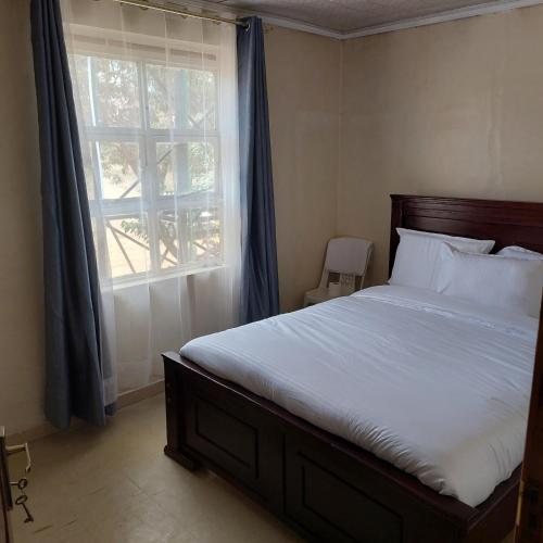 a bedroom with a large bed with a window at Crown Accommodation Narok in Narok